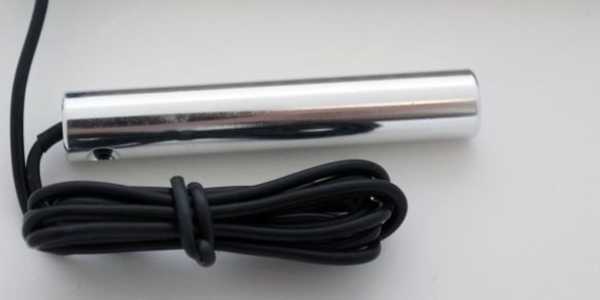 A close up of the top of a pen with a black cord.